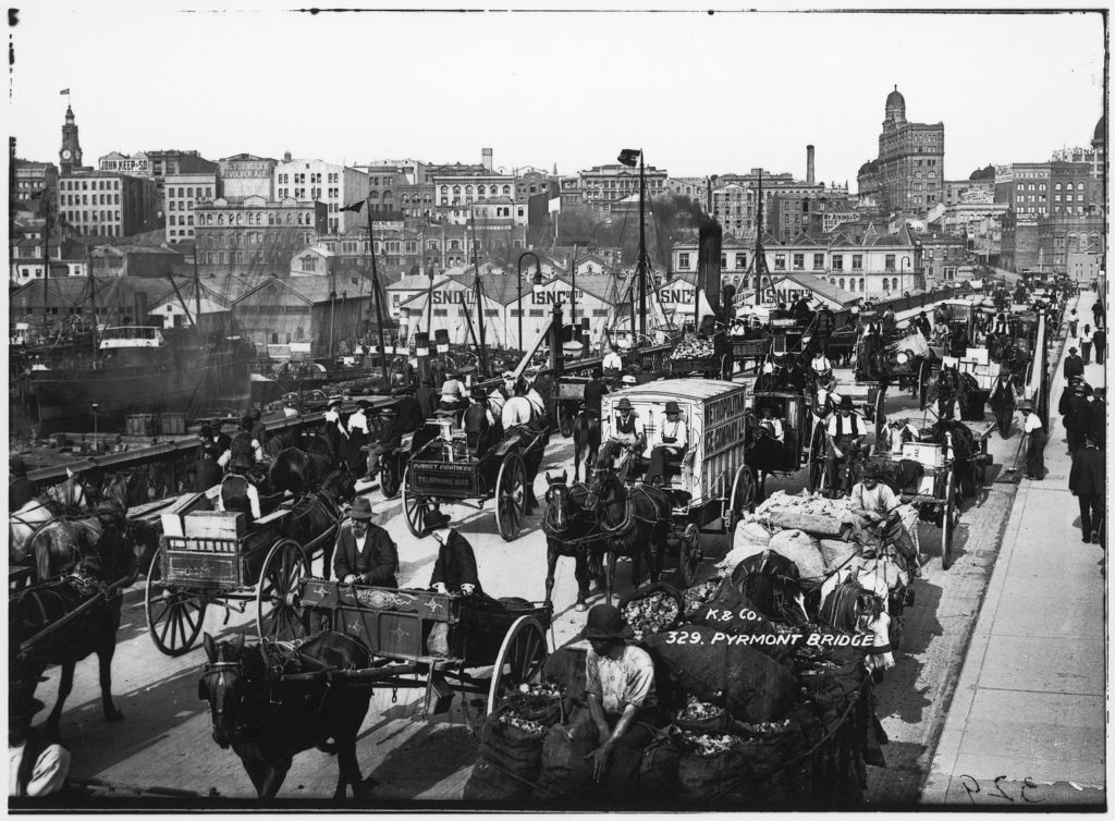 Black and white photo of a bridge filled with horse and carts and pedestrians